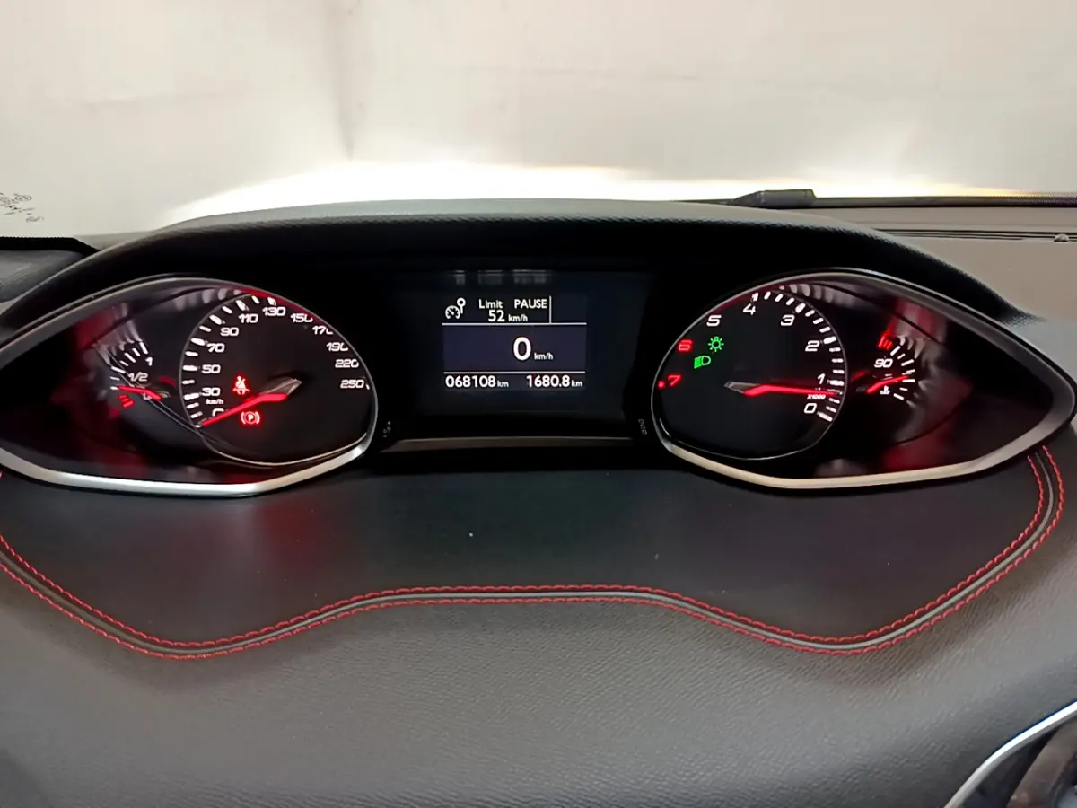 Vue rapprochée du tableau de bord de la Peugeot 308 gris foncé, affichage digital et compte-tours avec surpiqûres rouges.