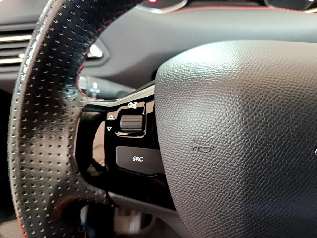 Gros plan sur le volant cuir perforé noir de la Peugeot 308 GT Line 2016 avec commandes intégrées côté gauche.