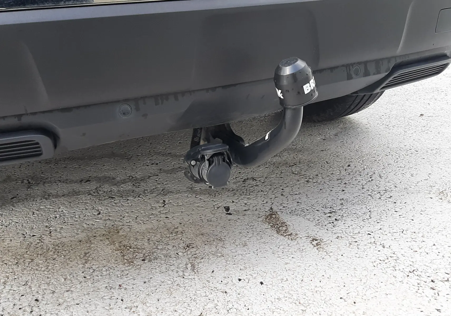 Gros plan sur l'attelage arrière noir du Peugeot 3008 gris Amazonite, mettant en valeur la prise électrique intégrée.