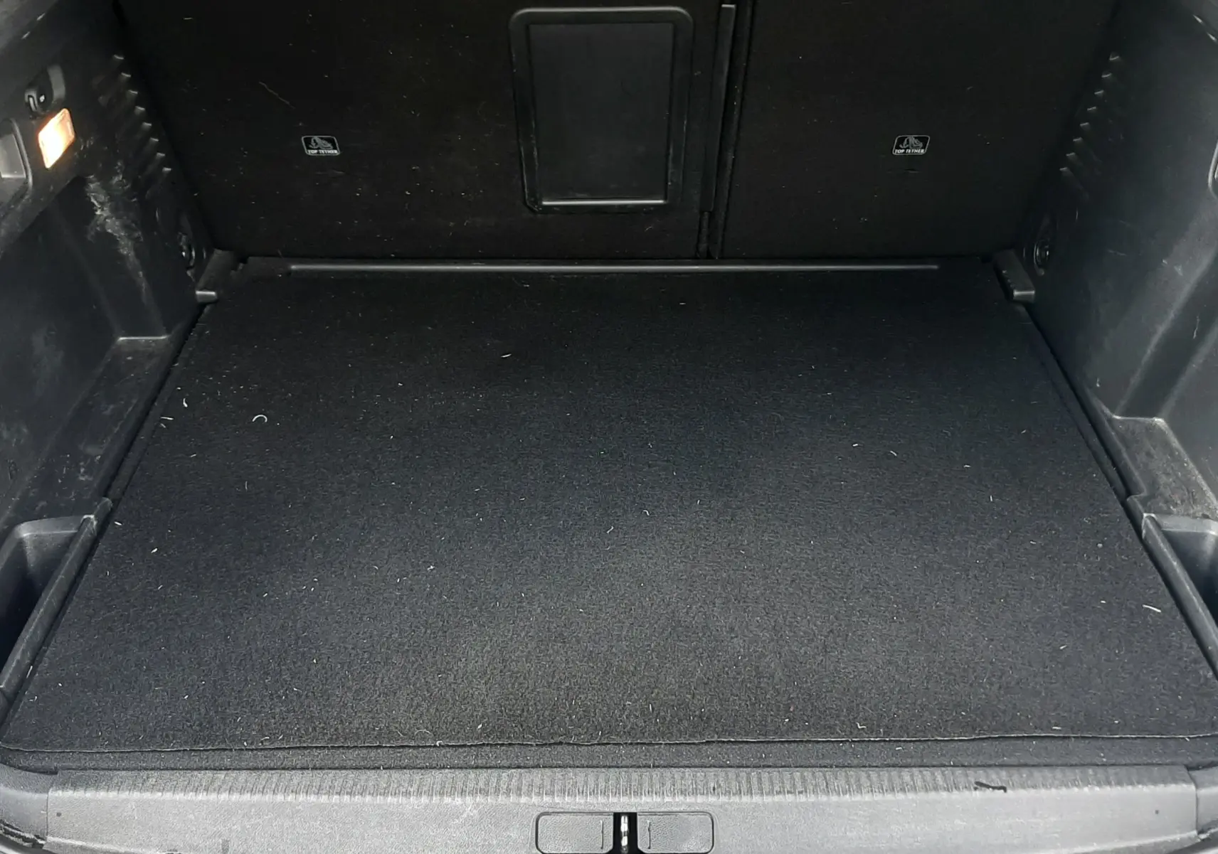 Coffre ouvert vu de face d’un Peugeot 3008 gris Amazonite, espace de chargement propre et tapis noir.