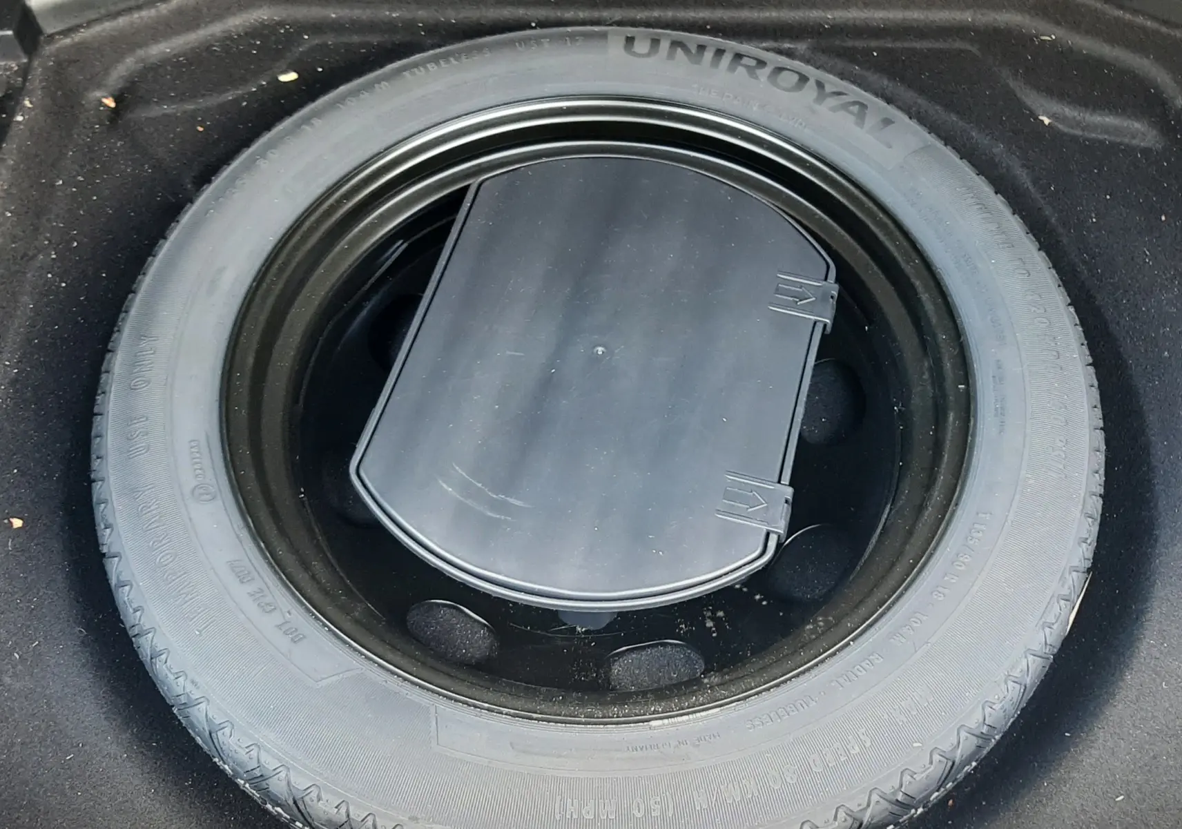 Roue de secours Uniroyal noire installée dans le coffre d'une Peugeot 3008 gris Amazonite, vue de dessus.
