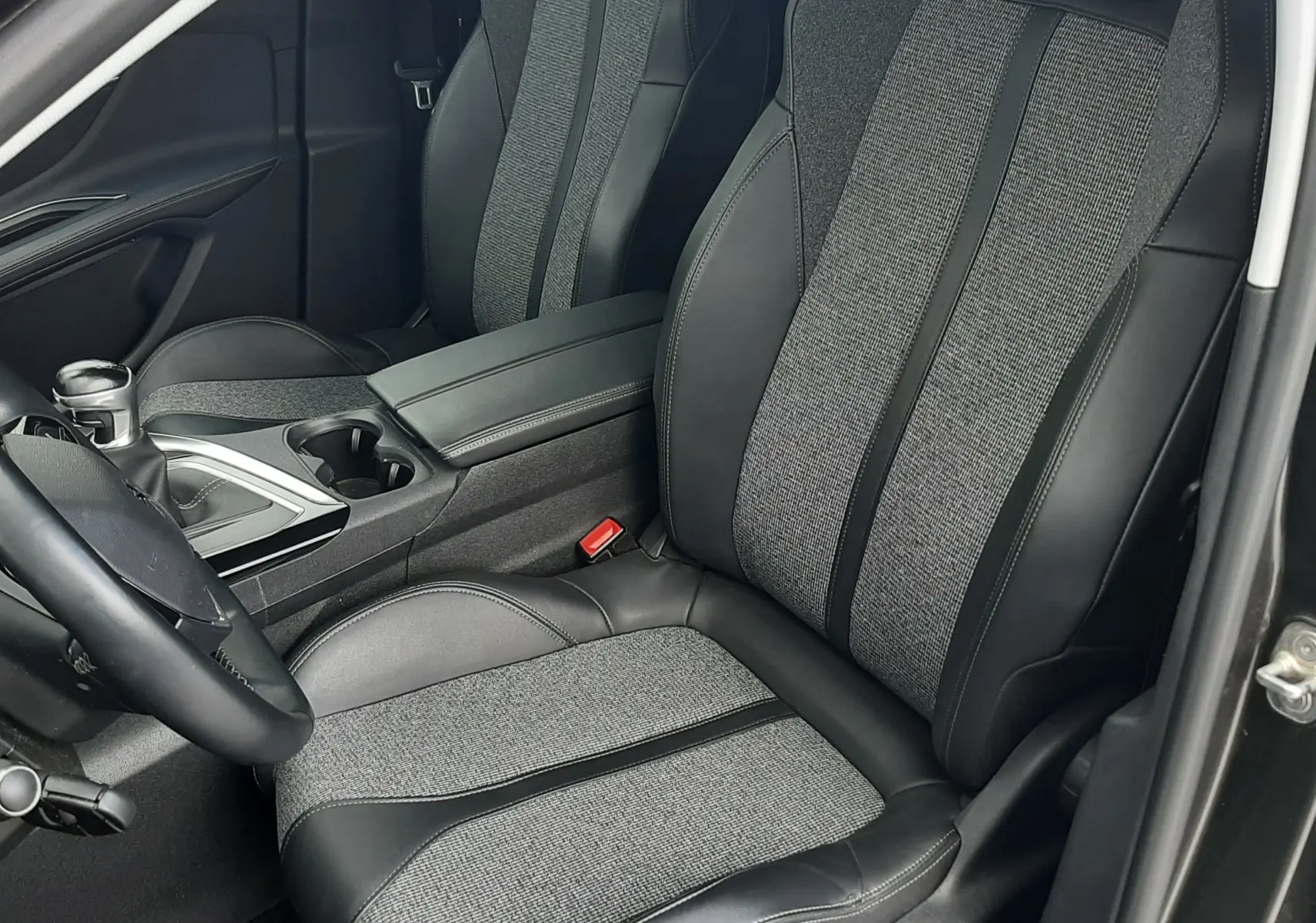 Vue intérieure côté conducteur du Peugeot 3008 2019, sièges tissu gris et cuir noir avec console centrale visible.
