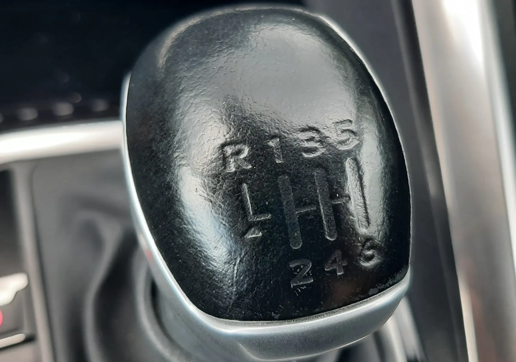 Gros plan sur le levier de vitesse manuel noir du Peugeot 3008 gris Amazonite, intérieur moderne avec finitions métalliques.