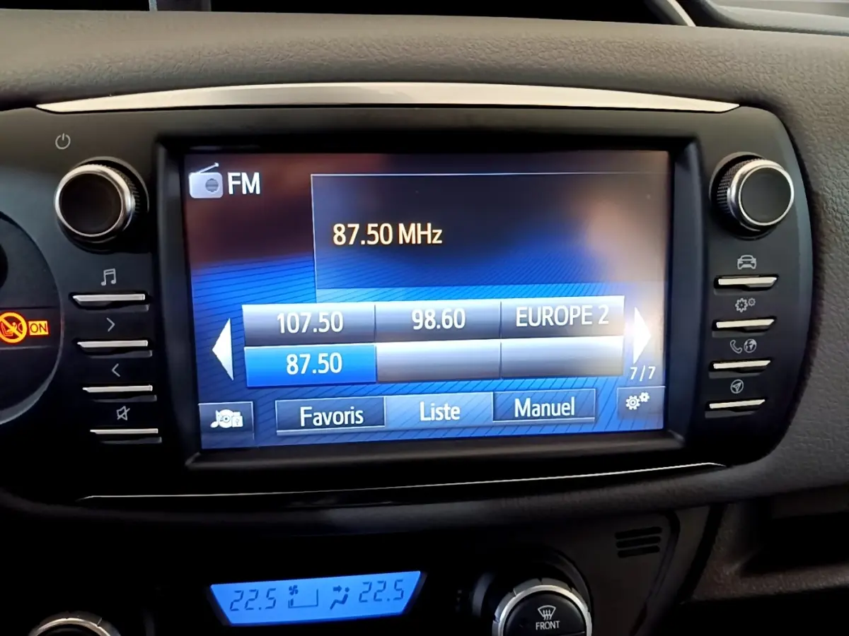 Écran tactile central de la Toyota Yaris blanche 2019 affichant la radio FM et commandes multimédia.