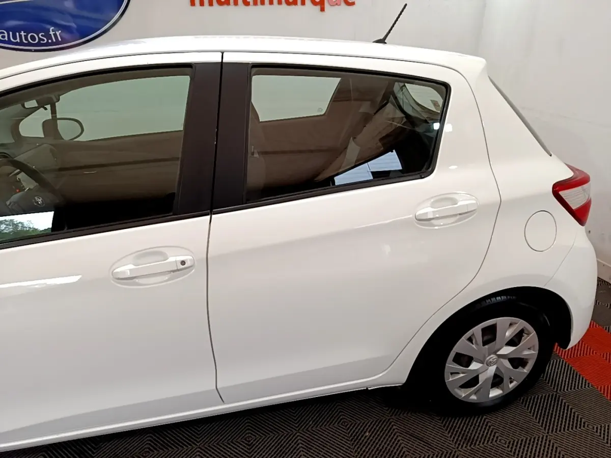 Vue latérale droite d'une Toyota Yaris blanche 2019, mettant en valeur les portières arrière et avant avec poignées intégrées.