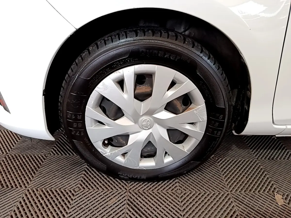 Gros plan sur la roue avant gauche blanche d'une Toyota Yaris 2019 avec enjoliveur argenté et pneu noir.