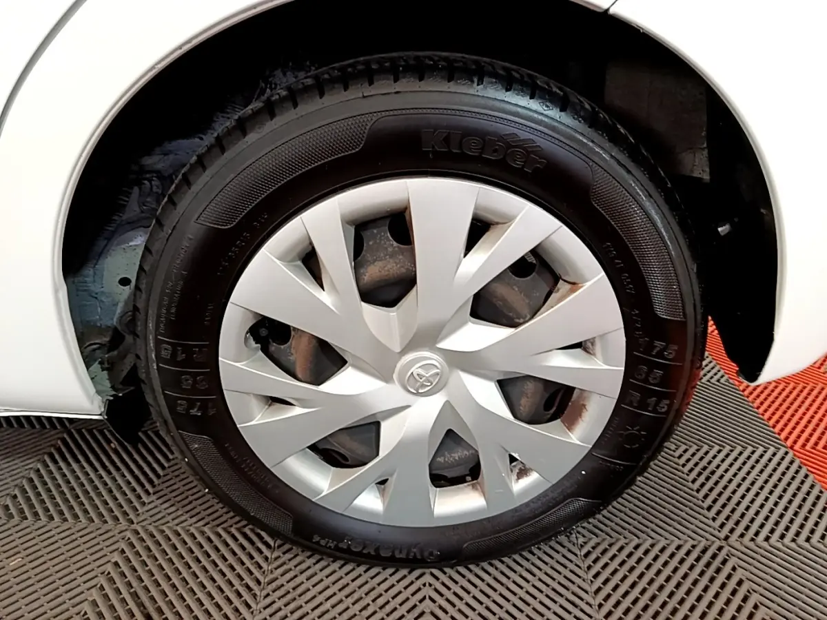 Gros plan sur la roue avant gauche blanche d'une Toyota Yaris 110 VVT-i CVT France Business avec enjoliveur argenté.