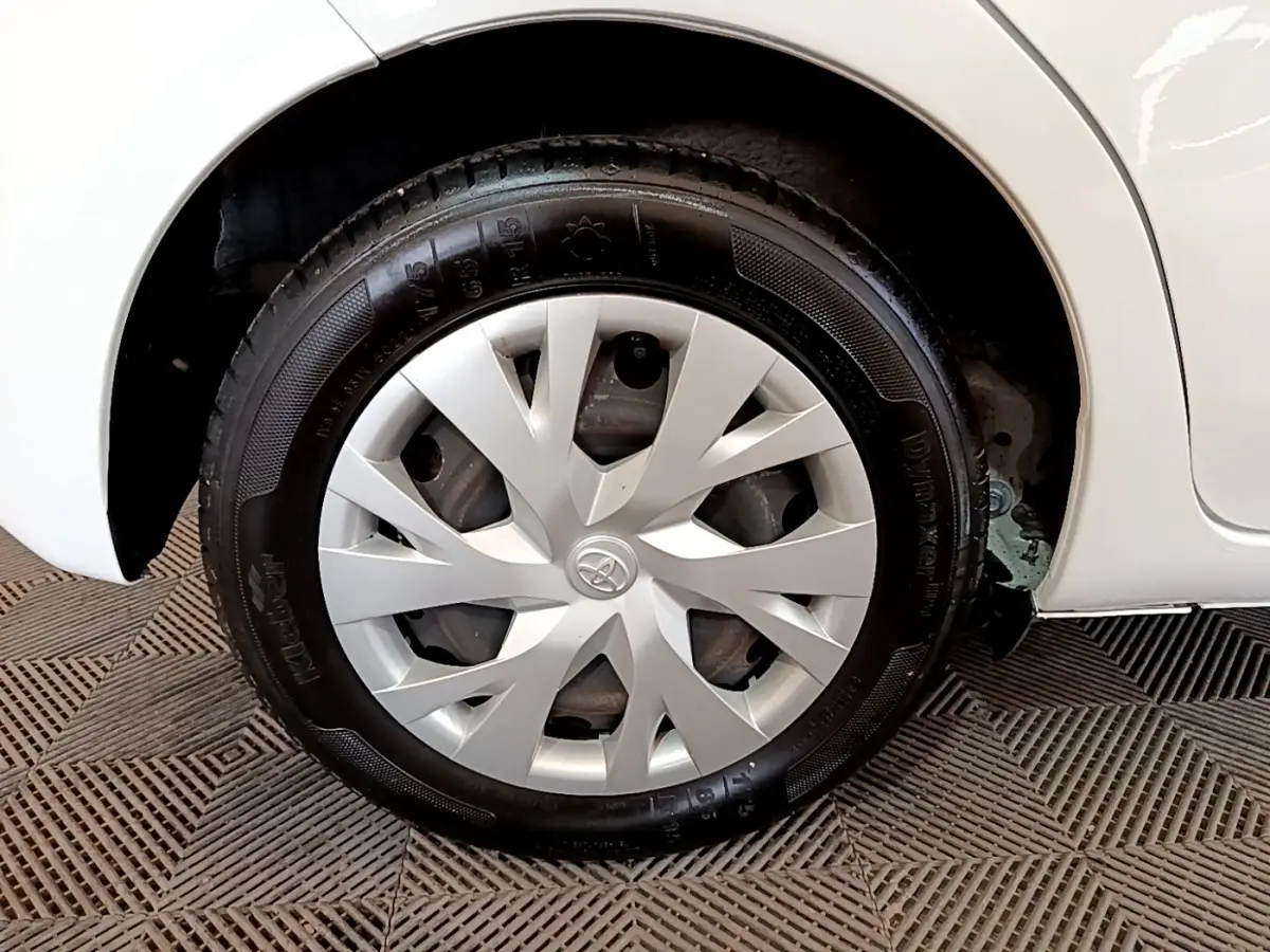 Gros plan sur la roue arrière droite blanche d'une Toyota Yaris 2019 avec enjoliveur argenté au design épuré.