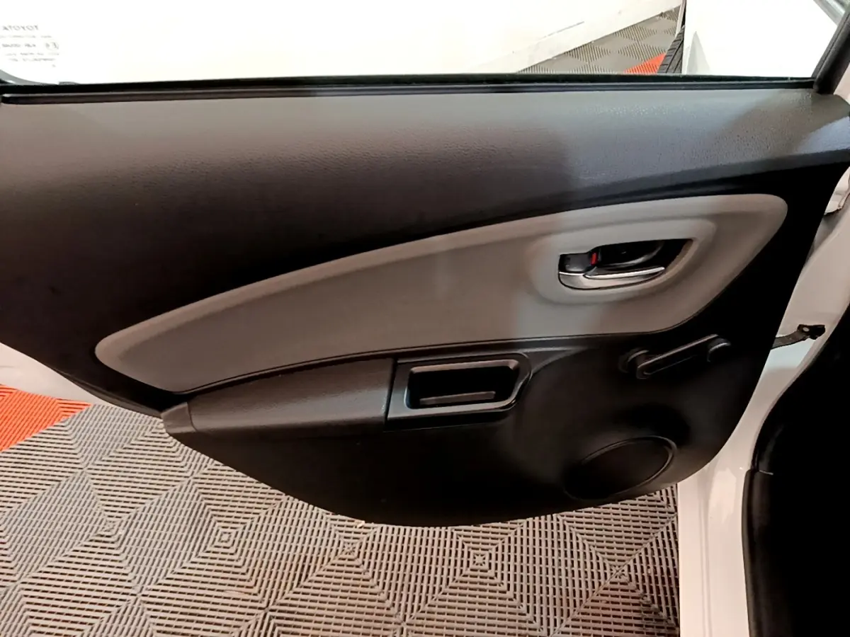 Vue intérieure côté gauche de la porte arrière blanche de la Toyota Yaris 2019 avec poignée et commande de vitre manuelle.