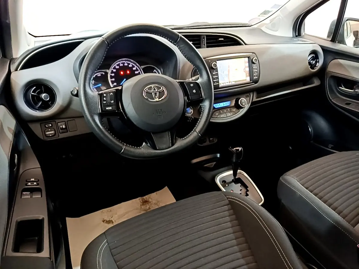 Vue intérieure avant droite de la Toyota Yaris 2019, volant cuir multifonctions et écran tactile de navigation visible.