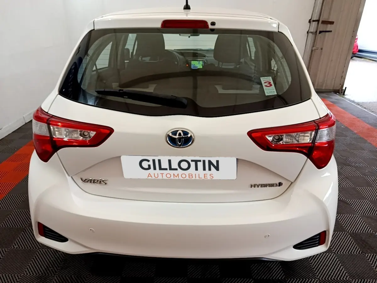 Vue arrière d'une Toyota Yaris blanche hybride 2019, avec feux arrière distinctifs et logo Toyota visible.