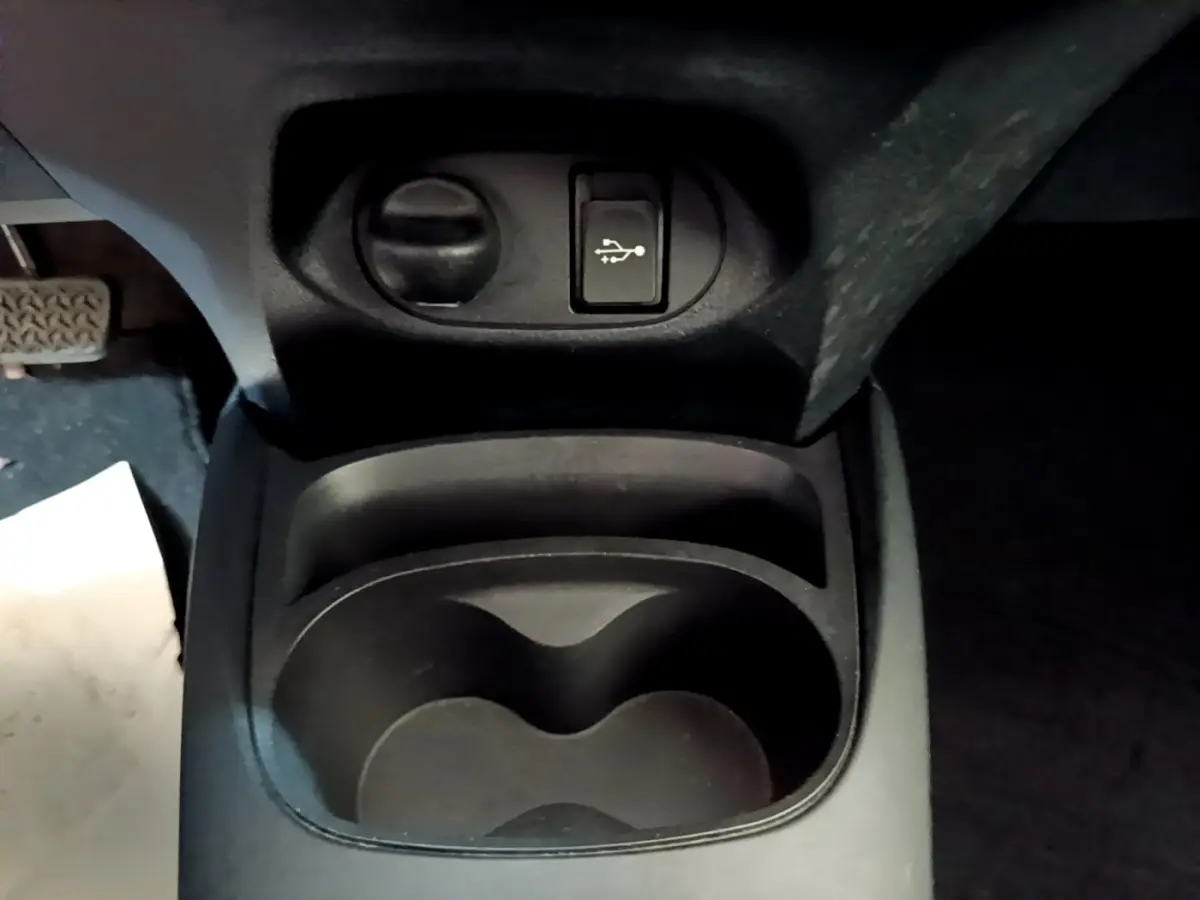 Vue rapprochée de la console centrale noire de la Toyota Yaris 2019, avec prise USB et porte-gobelets.