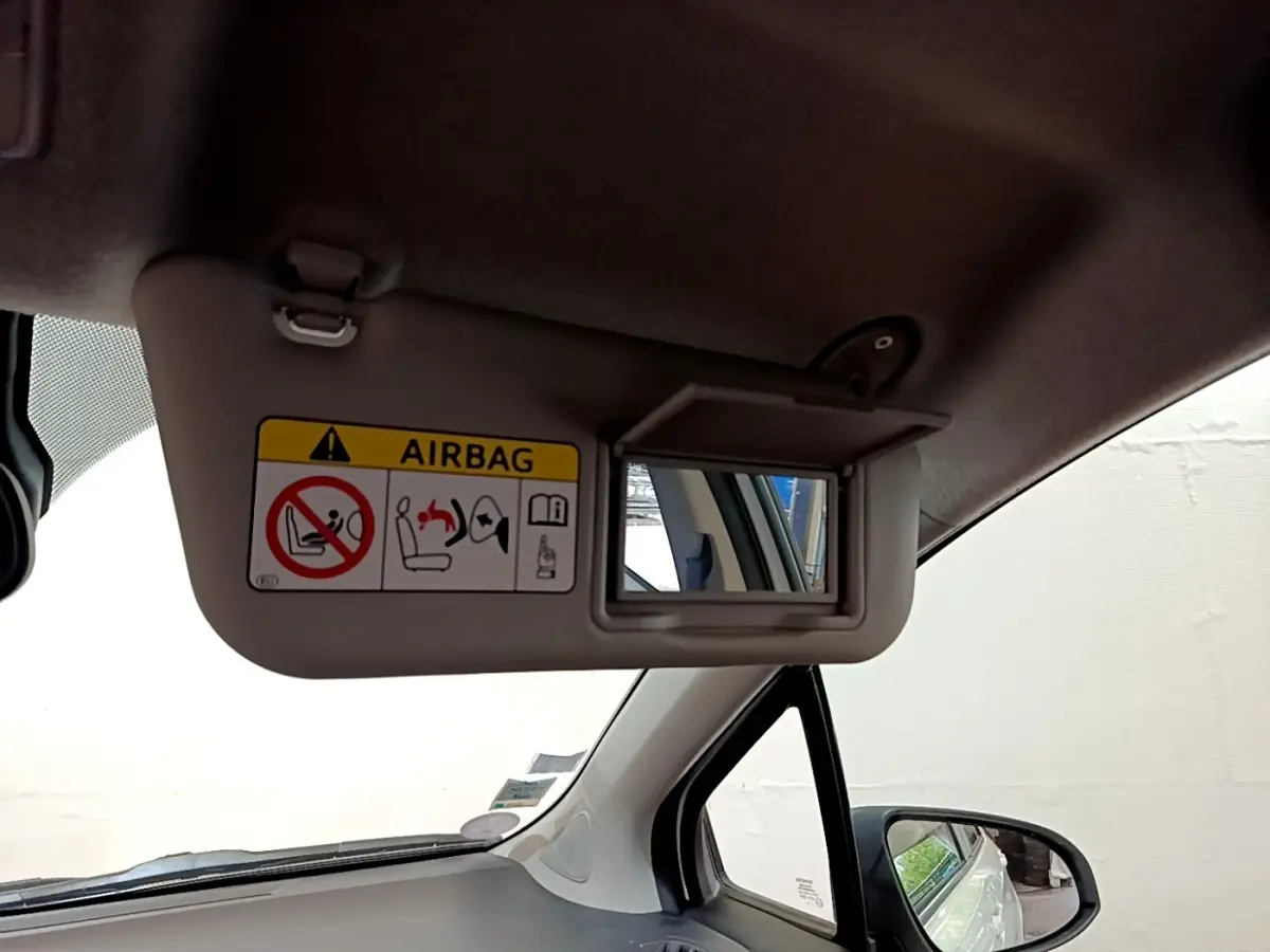 Intérieur côté conducteur de la Toyota Yaris blanche 2019, avec pare-soleil et miroir de courtoisie ouvert.