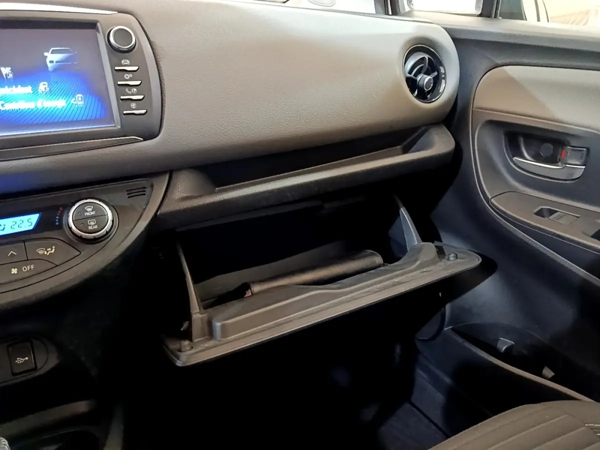 Intérieur noir de la Toyota Yaris 2019, vue côté passager avec boîte à gants ouverte et écran tactile allumé.