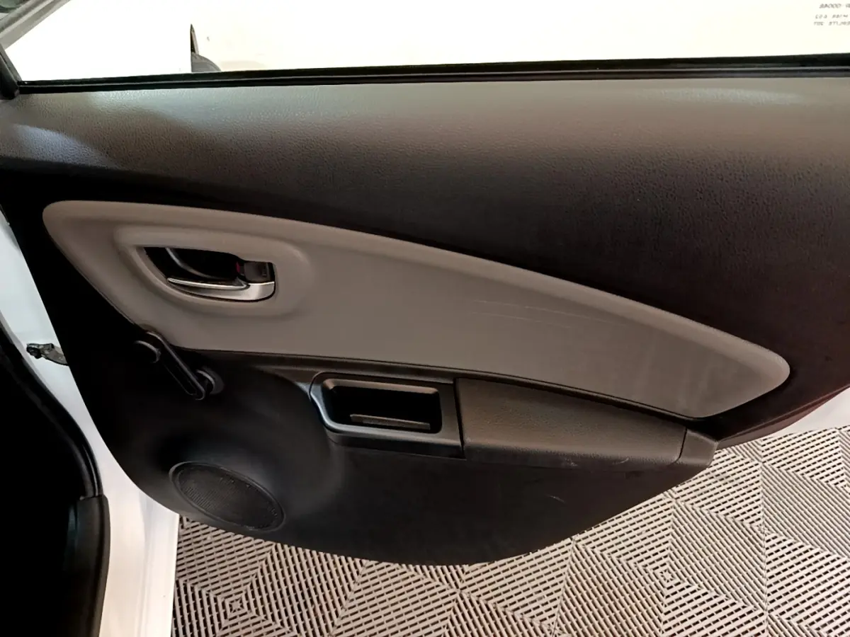 Vue intérieure côté gauche de la porte avant blanche d'une Toyota Yaris 2019 avec poignée et haut-parleur intégrés.