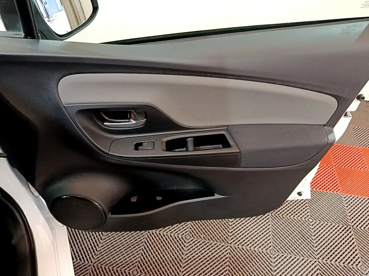 Vue rapprochée de la porte avant gauche blanche de la Toyota Yaris 2019 avec panneau intérieur noir et gris.