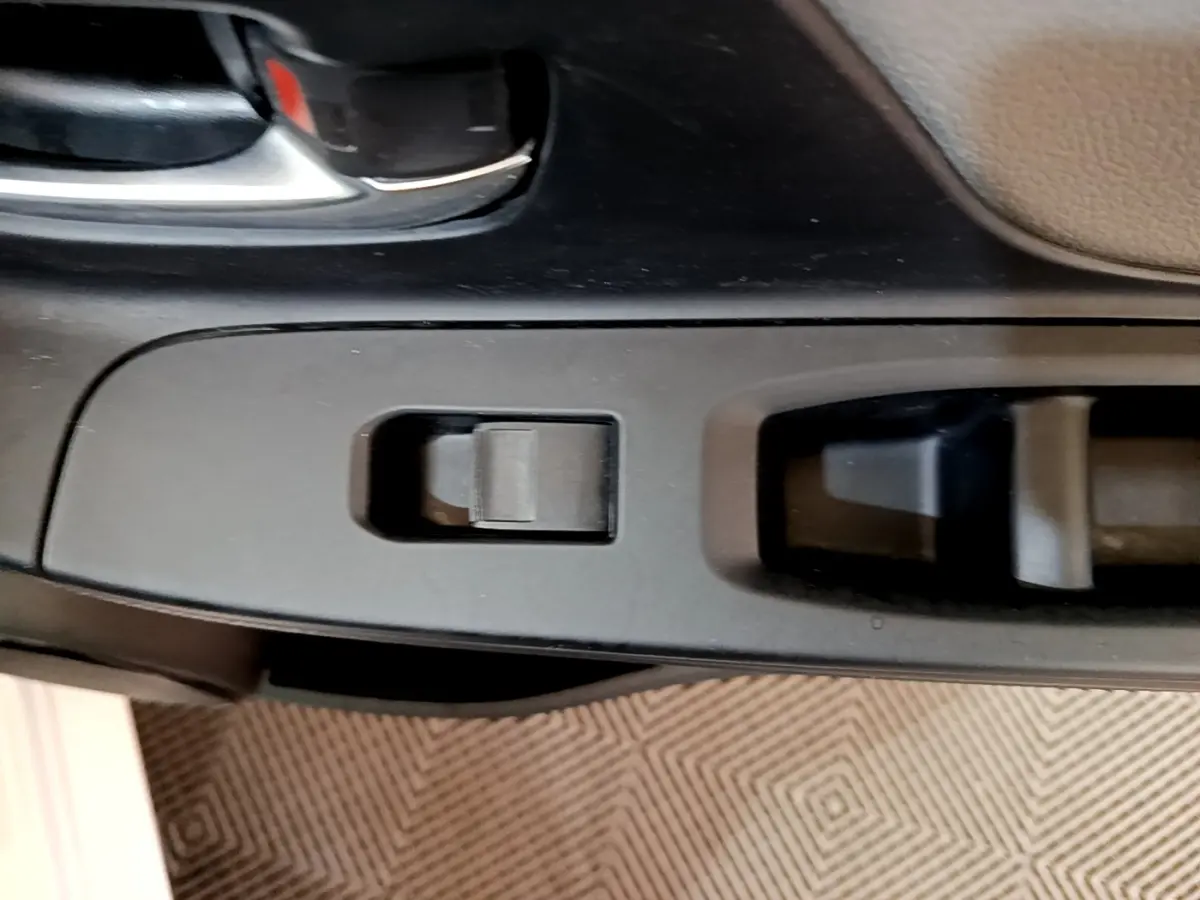 Détail de la commande de lève-vitre côté conducteur dans l’habitacle noir de la Toyota Yaris blanche 2019.
