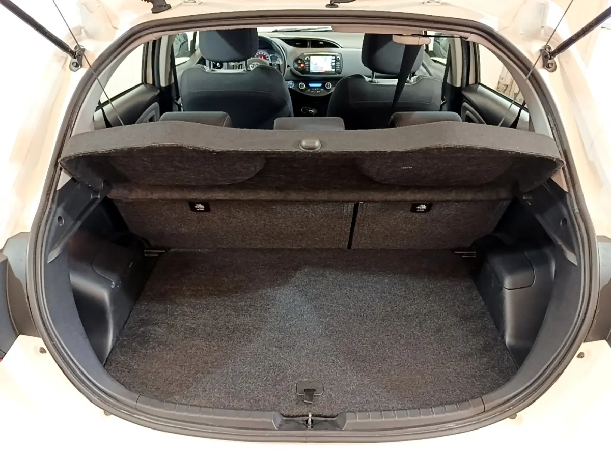 Vue arrière du coffre ouvert d'une Toyota Yaris blanche 2019, avec banquette arrière et tableau de bord visibles.
