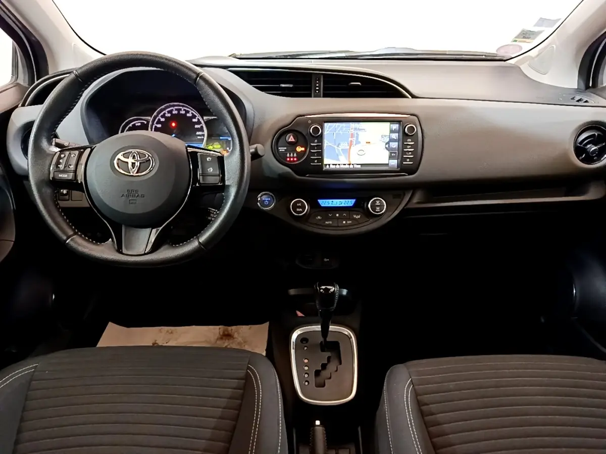 Vue intérieure avant de la Toyota Yaris 2019, tableau de bord noir avec écran tactile et volant multifonctions cuir alu.