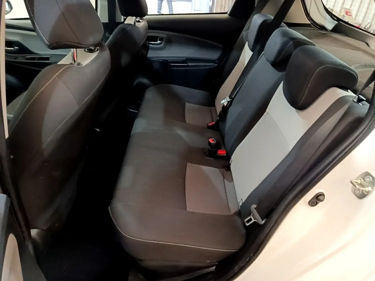 Vue intérieure arrière droite de la Toyota Yaris blanche 2019, montrant la banquette bi-ton noire et grise avec appuie-têtes.