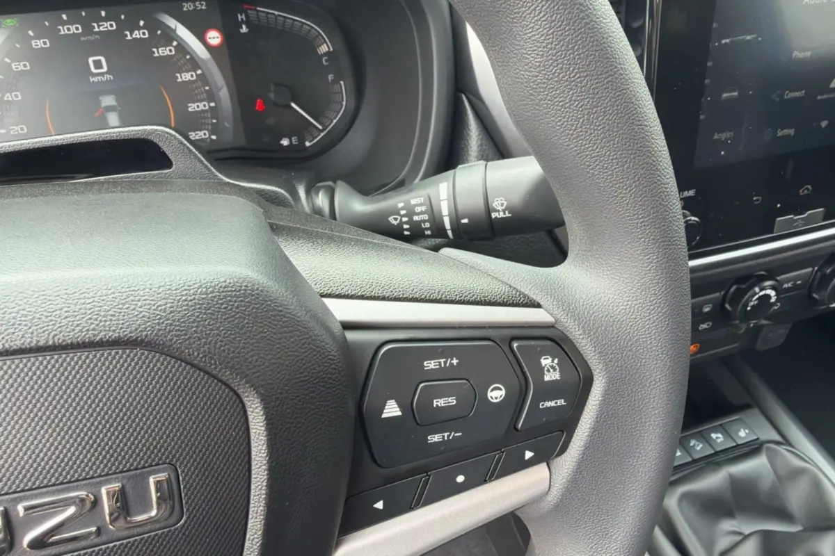 Gros plan sur le volant multifonctions et tableau de bord du pick-up Isuzu D-MAX 2026, intérieur noir.