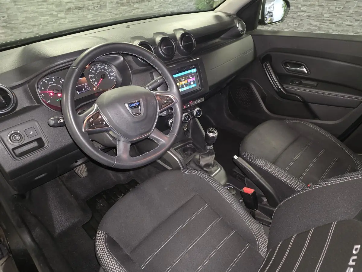 Vue intérieure côté conducteur du Dacia Duster 2019 avec tableau de bord noir et volant multifonction.