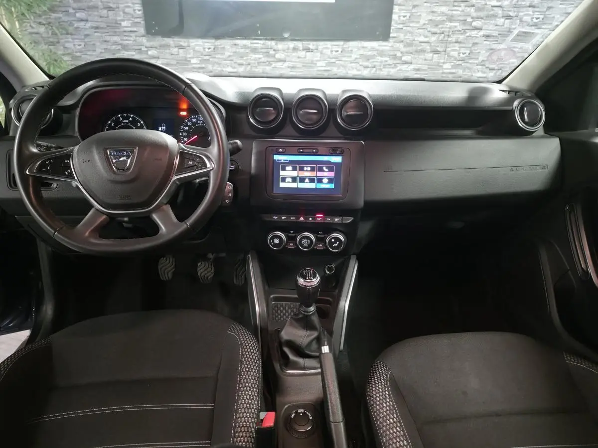 Vue intérieure avant du Dacia Duster 2019 noir, avec volant multifonction, écran tactile et boîte manuelle.