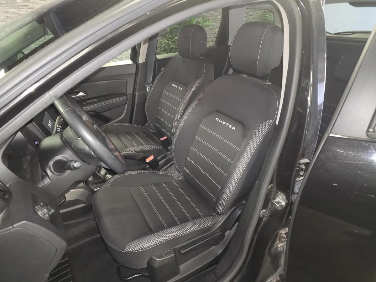 Vue intérieure côté conducteur du Dacia Duster noir 2019, sièges tissu avec logo Duster brodé.