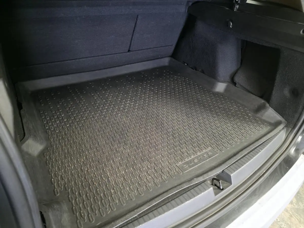 Vue intérieure du coffre du Dacia Duster 2019 avec tapis de protection en caoutchouc noir marqué Duster.