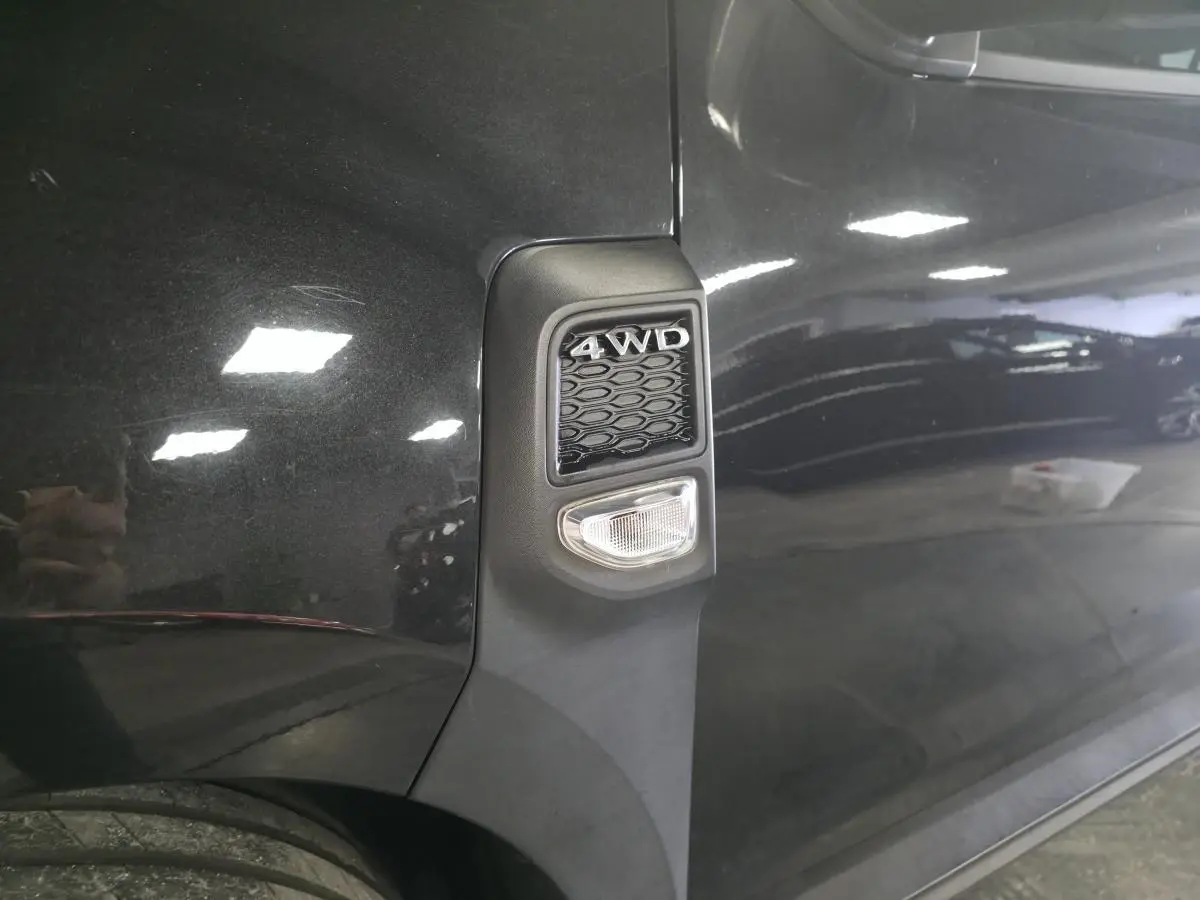Gros plan sur l'aile avant gauche noire nacrée du Dacia Duster 1.3 TCe 4x4 avec badge 4WD et répétiteur latéral.