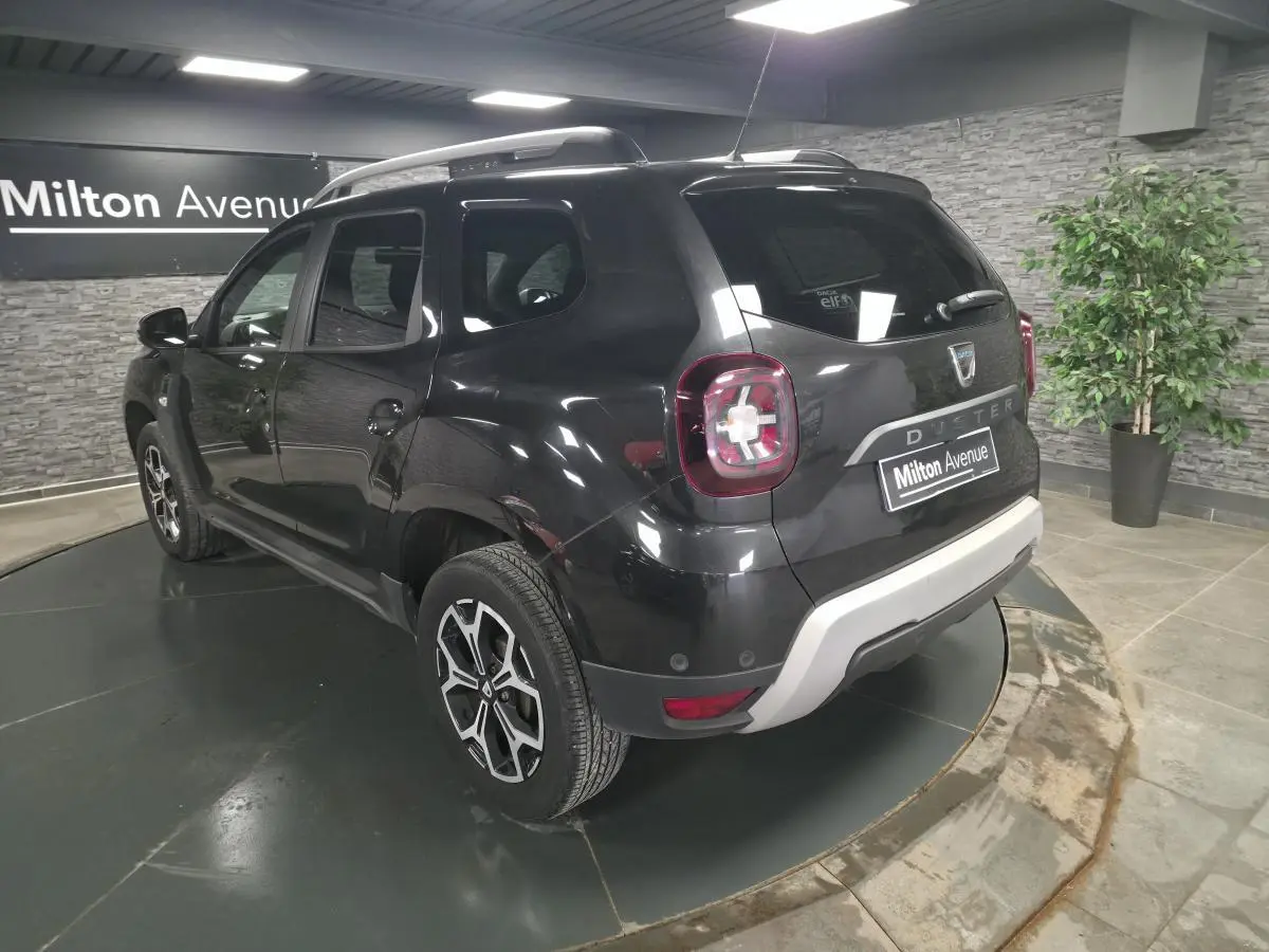 Vue 3/4 arrière droite du Dacia Duster noir nacré 2019 avec jantes alliage et bouclier arrière gris clair.