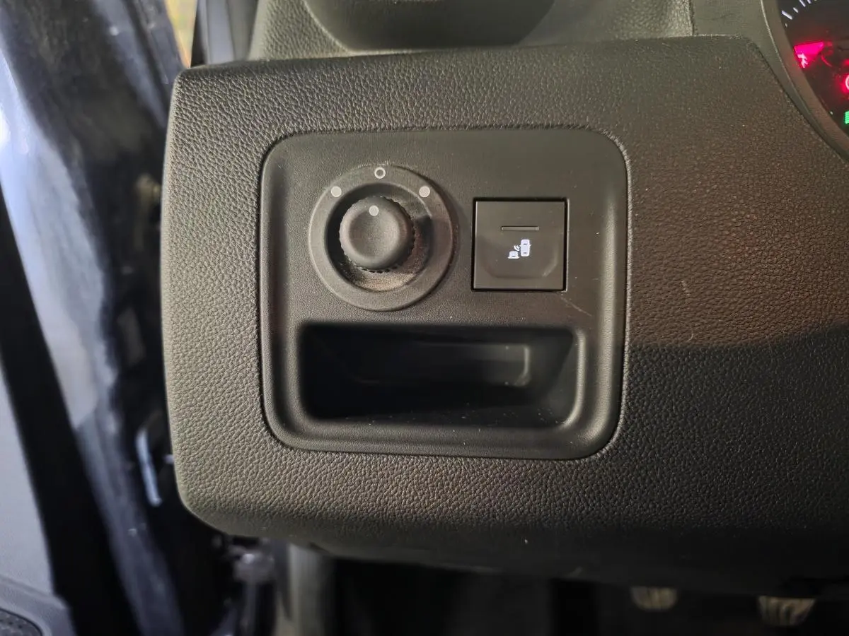 Gros plan sur le tableau de bord côté gauche du Dacia Duster noir 2019, bouton réglage des rétroviseurs et ouverture du coffre.