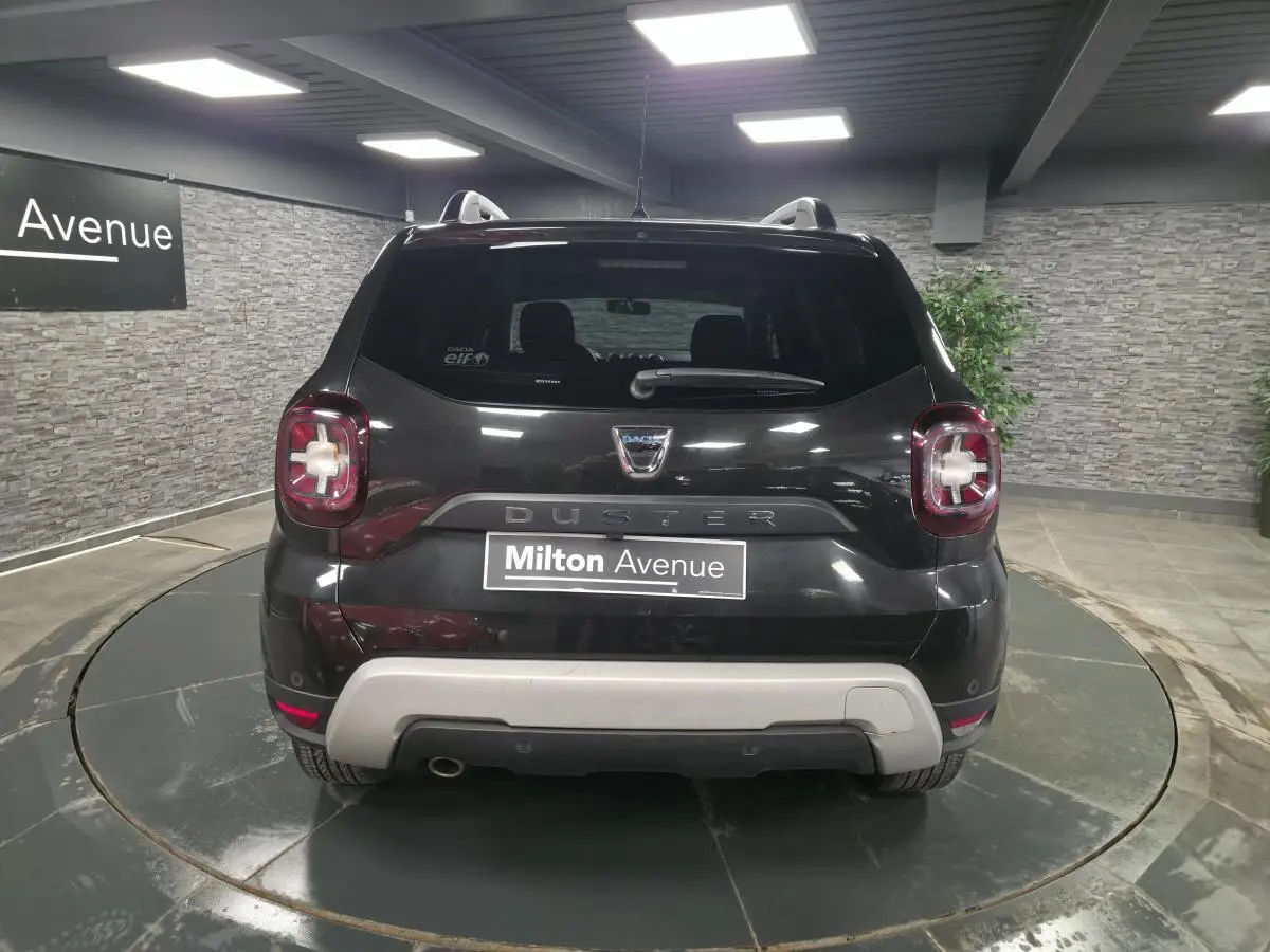 Vue arrière d'un Dacia Duster noir nacré 2019 avec bouclier arrière gris et feux distinctifs en intérieur rouge.