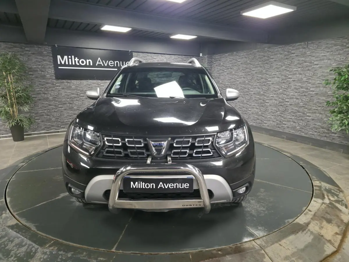 Vue avant d'un Dacia Duster noir nacré 2019 avec calandre chromée et protection de pare-chocs en métal.
