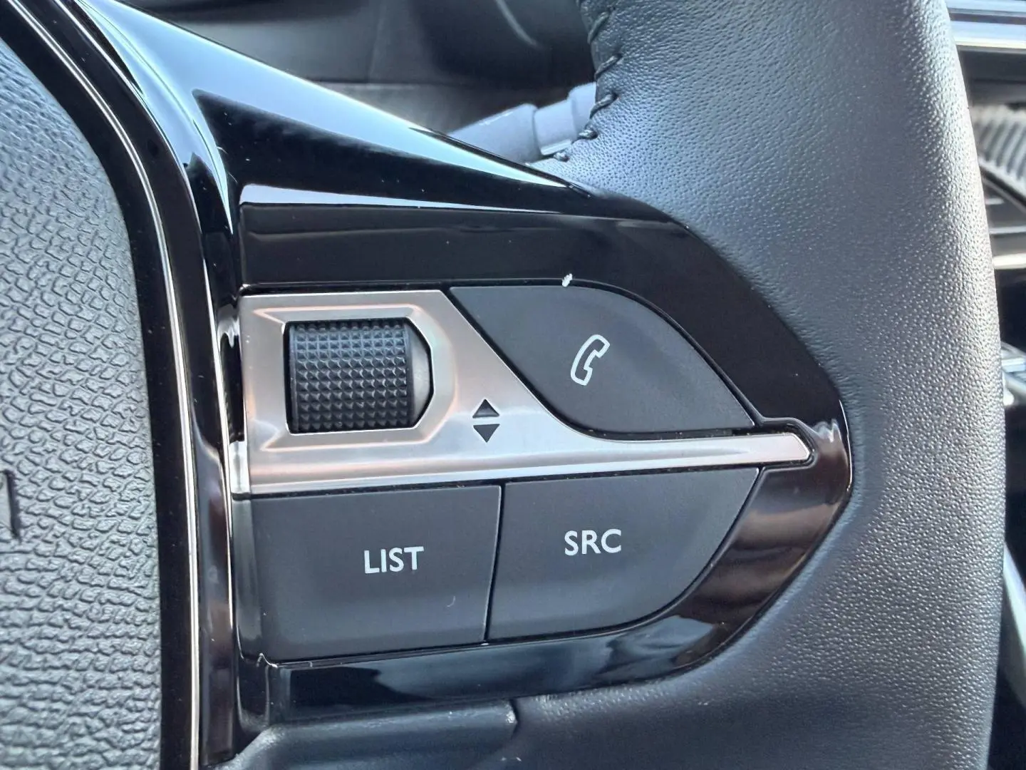 Gros plan sur les commandes audio et téléphone au volant noir de la Peugeot 208 1.2 100ch Allure 2025.