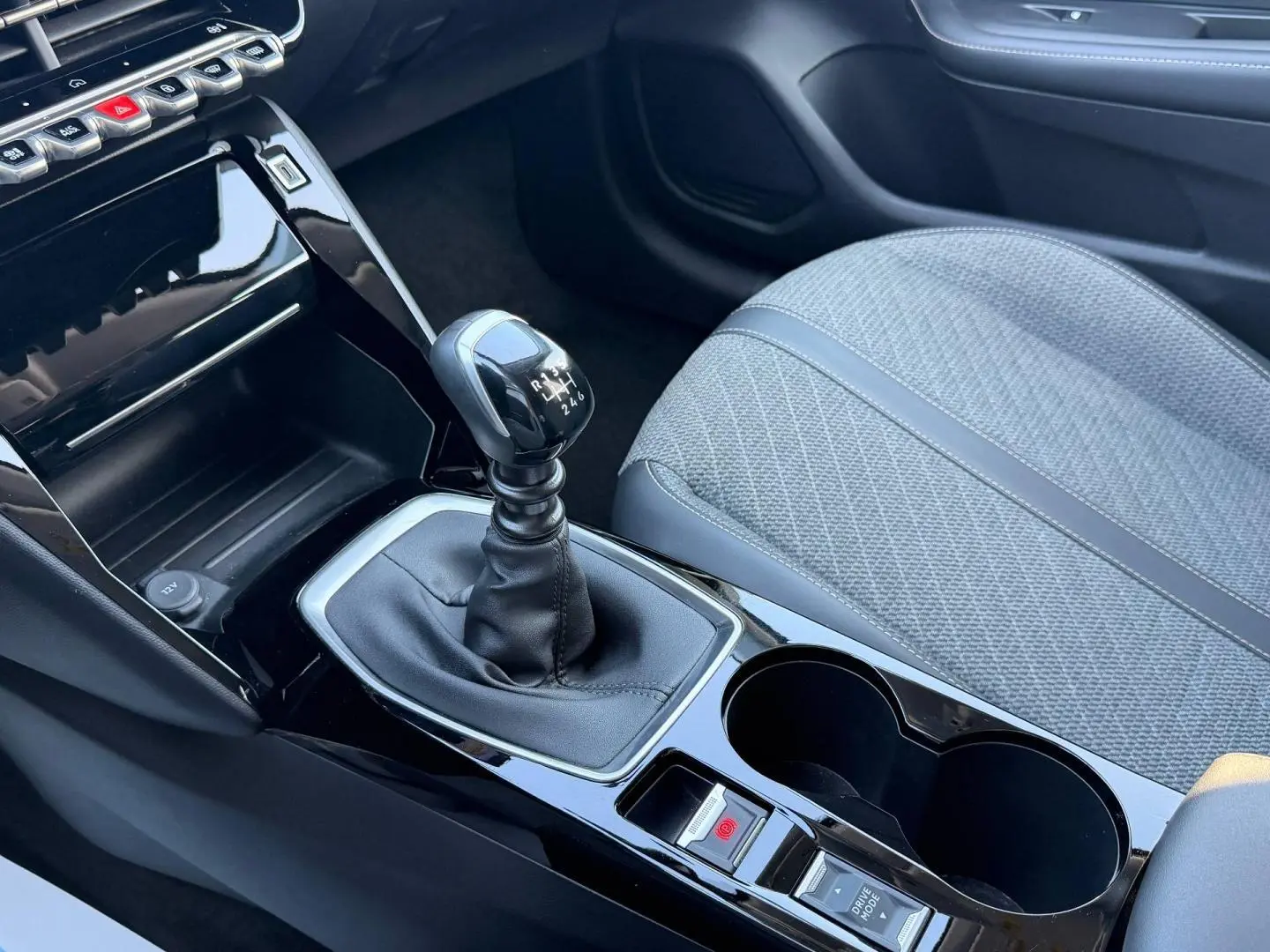 Gros plan sur la console centrale et levier de vitesses manuelle de la Peugeot 208 1.2 100ch Allure avec siège tissu gris.