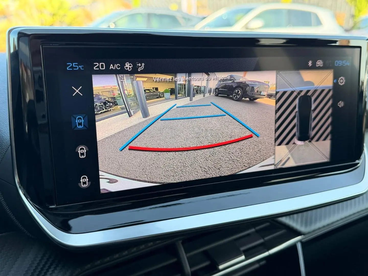 Écran tactile intérieur montrant la caméra de recul et l'aide au stationnement du Peugeot 208 gris Selenium.