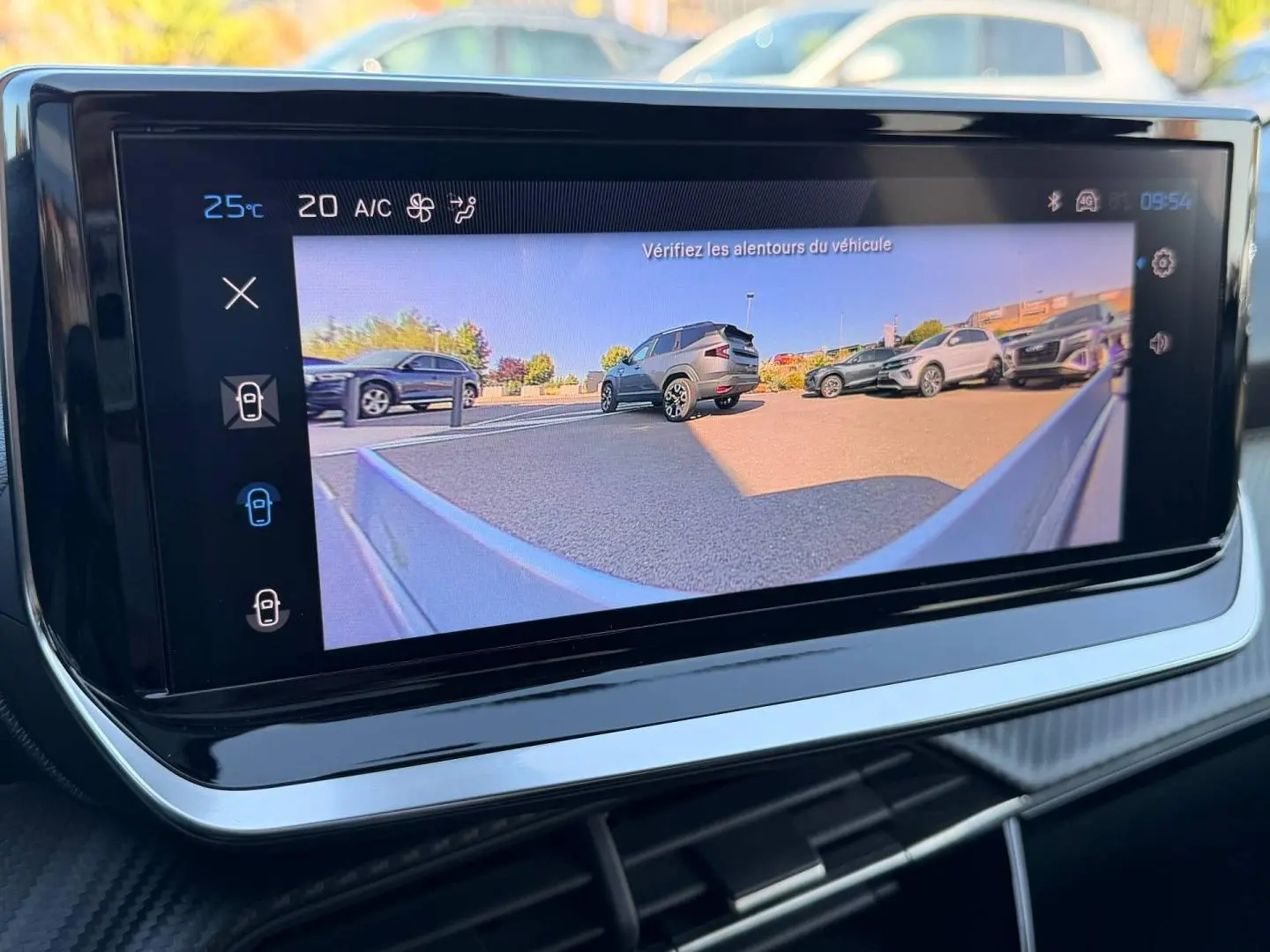 Écran tactile intérieur montrant la caméra de recul avec vue sur plusieurs véhicules en stationnement.