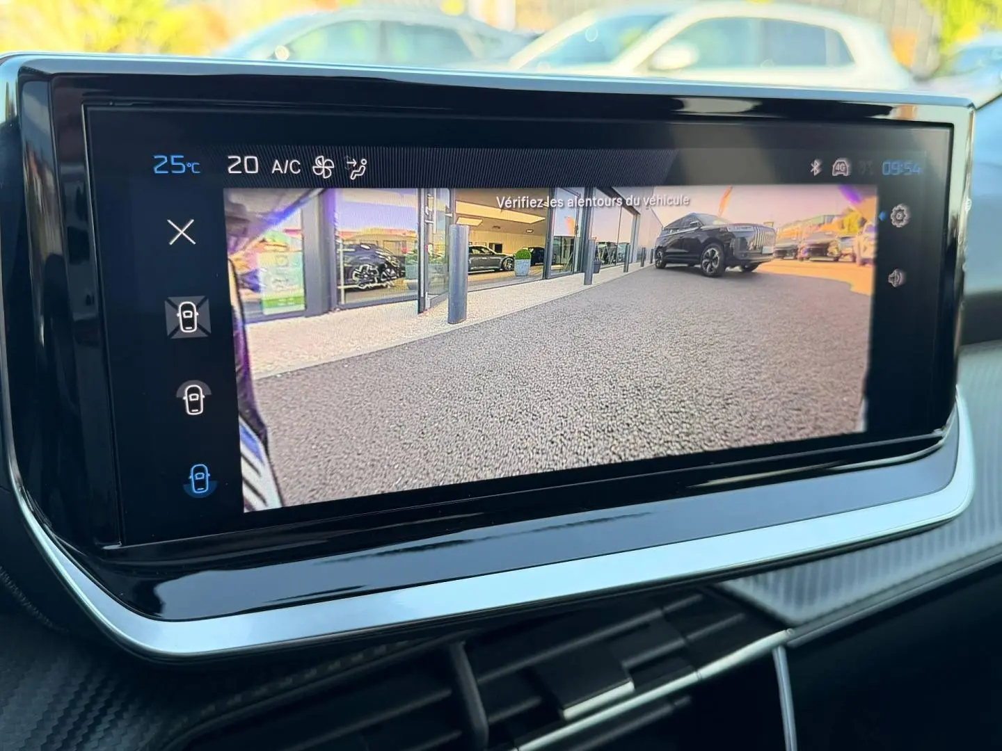 Écran tactile intérieur affichant la caméra de recul avec vue arrière sur un sol goudronné et un SUV noir.