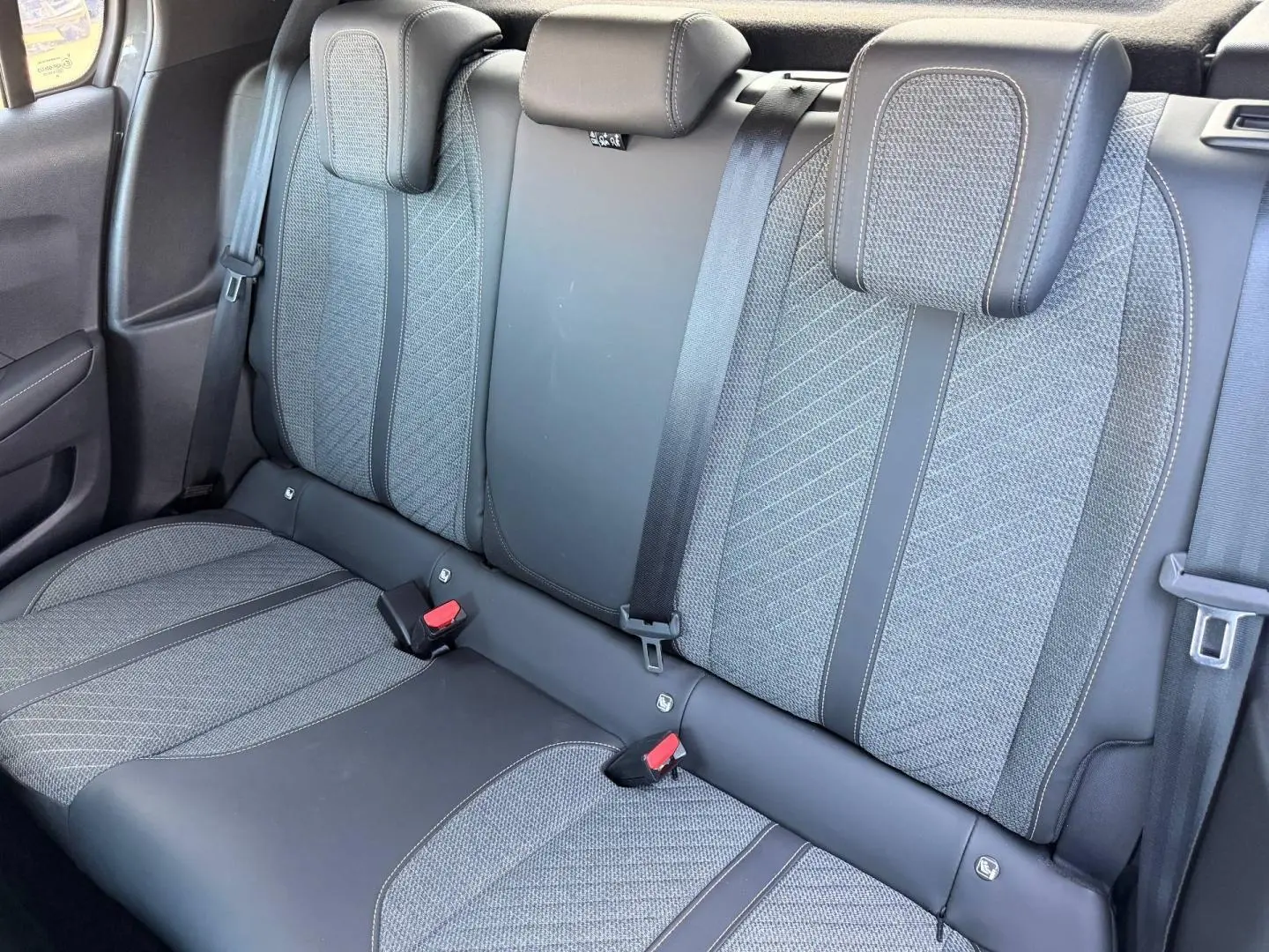 Vue rapprochée de la banquette arrière grise tissu et cuir de la Peugeot 208 1.2 100ch Allure 2025, avec ceintures et appuie-têtes.