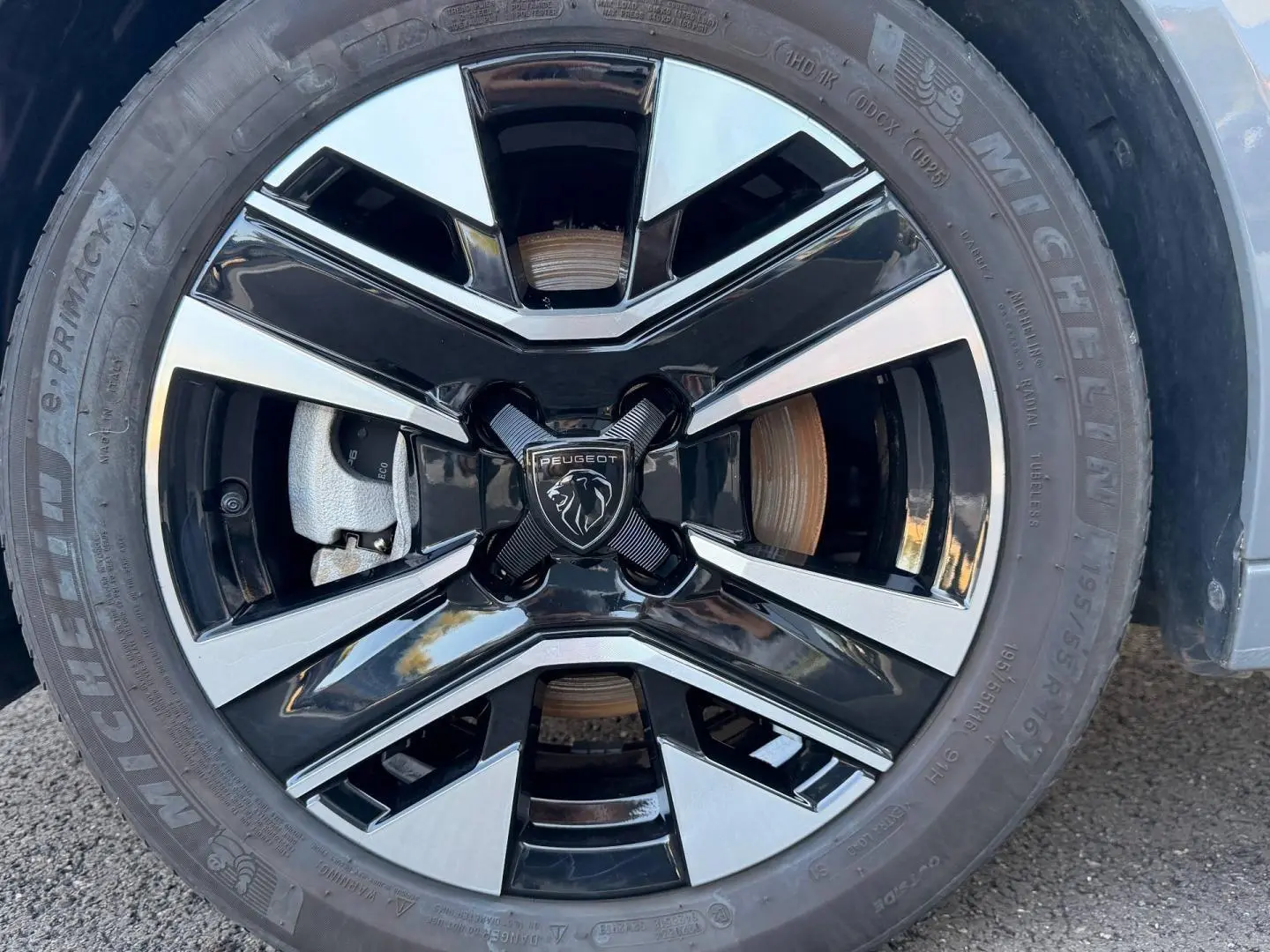 Gros plan sur la jante alu bicolore noire et argentée d’une Peugeot 208 Gris Selenium, avec logo lion central.