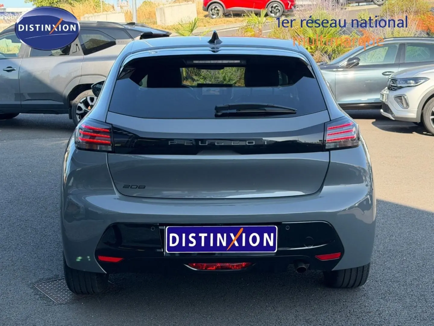 Vue arrière d'une Peugeot 208 gris Selenium avec feux arrière LED et plaque Distinxion visible en extérieur.