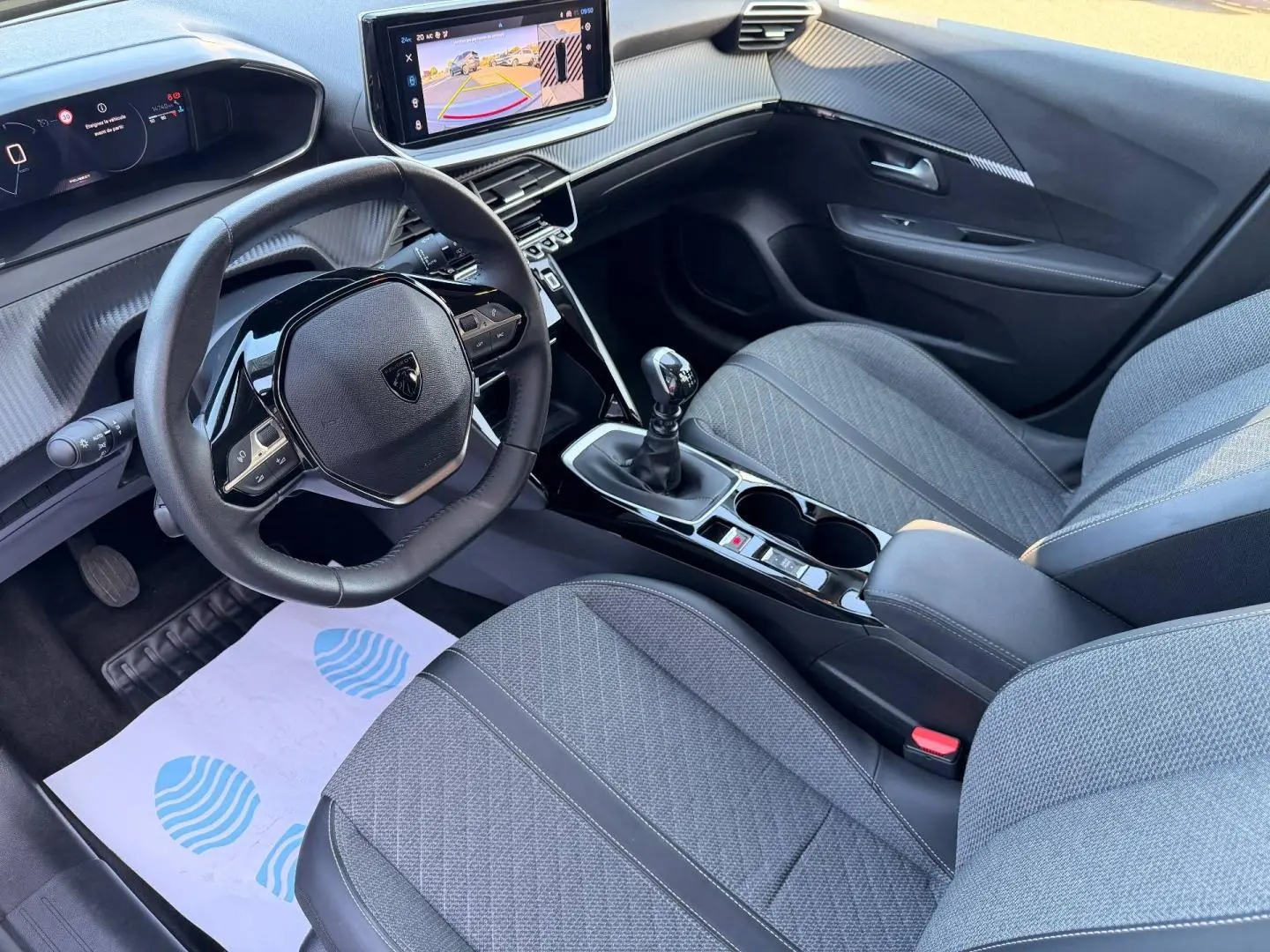 Intérieur avant droit de la Peugeot 208 gris Selenium avec volant compact, écran tactile et boîte manuelle.