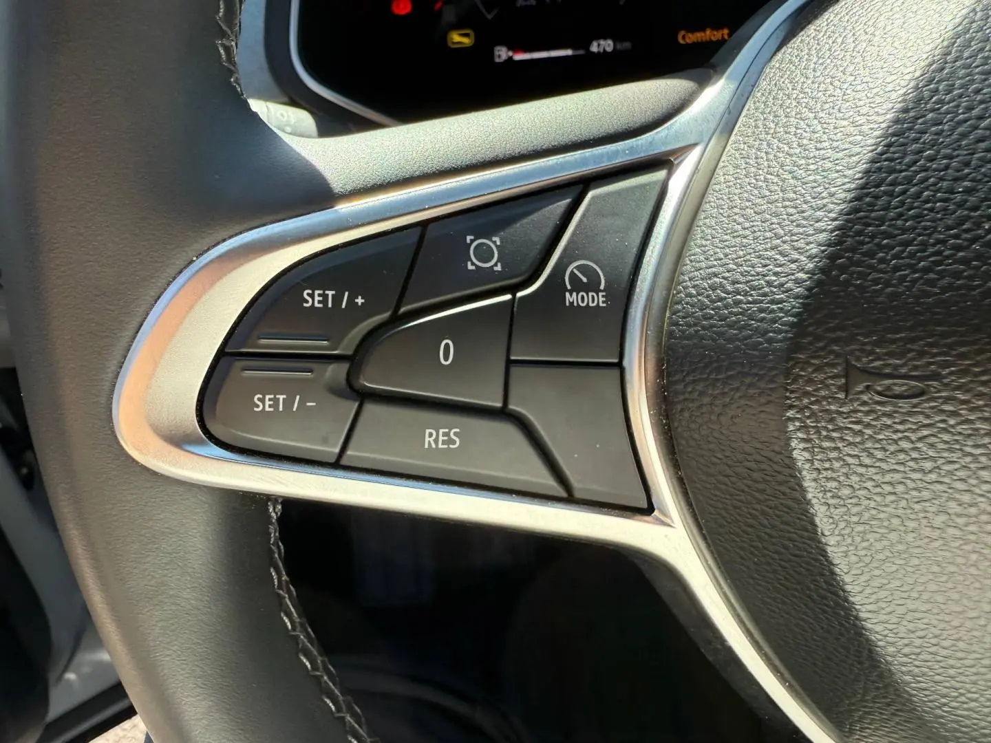 Gros plan sur les commandes de régulateur de vitesse à gauche du volant noir du Renault Captur gris Rafale métallisé.