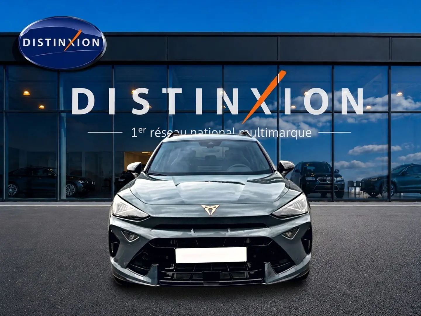 Vue frontale d'une CUPRA Formentor 1.5 etsi hybrid 150 DSG7 en bleu fjord devant une vitrine Distinxion.