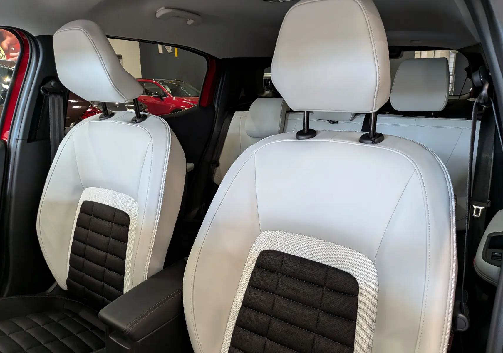 Vue rapprochée des sièges avant en cuir noir et blanc du Citroën C3 Aircross Hybride 2026 avec intérieur lumineux.