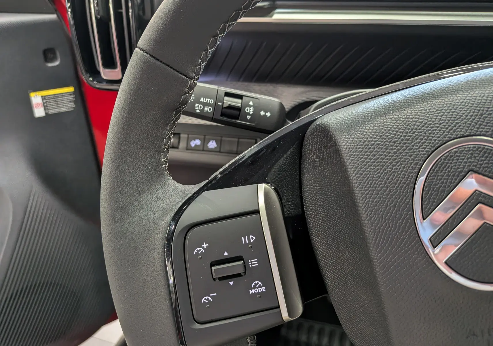 Gros plan sur le volant côté gauche du Citroën C3 Aircross rouge Elixir avec commandes intégrées et logo Citroën visible.