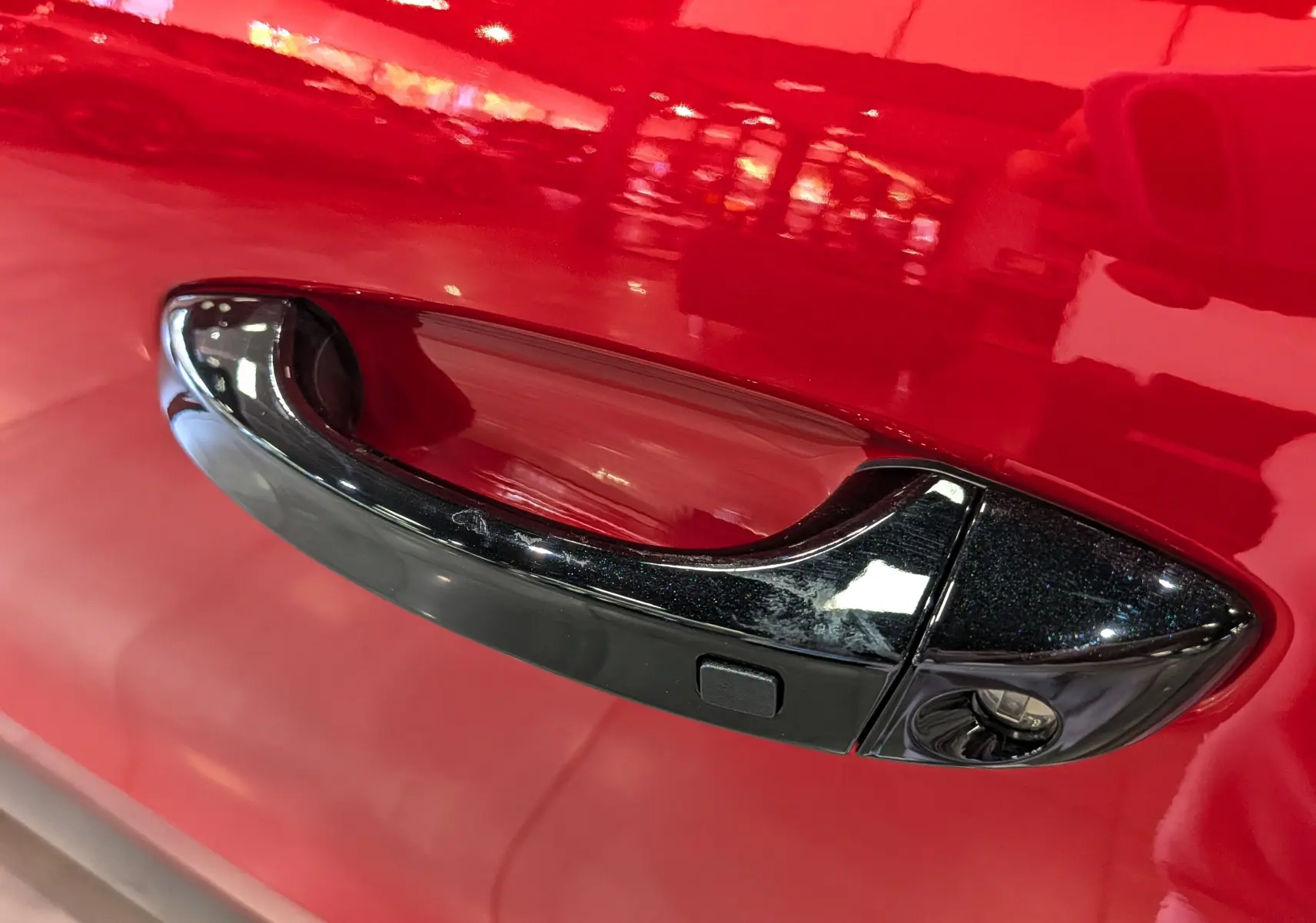 Poignée de porte noire en gros plan sur la porte rouge Elixir d'une Citroën C3 Aircross hybride 2026.