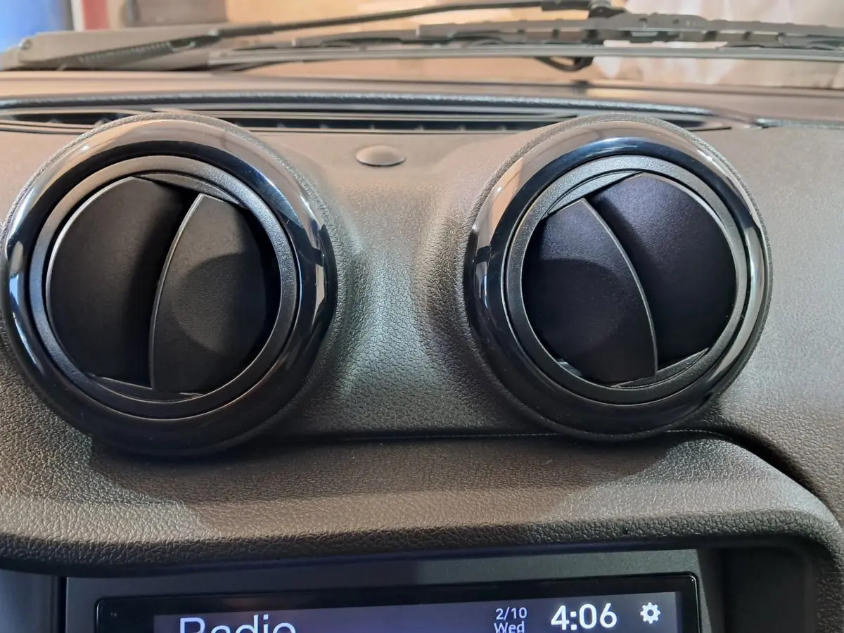 Gros plan sur les deux aérateurs ronds noirs du tableau de bord de l'AIXAM AMBITION rouge 2025.