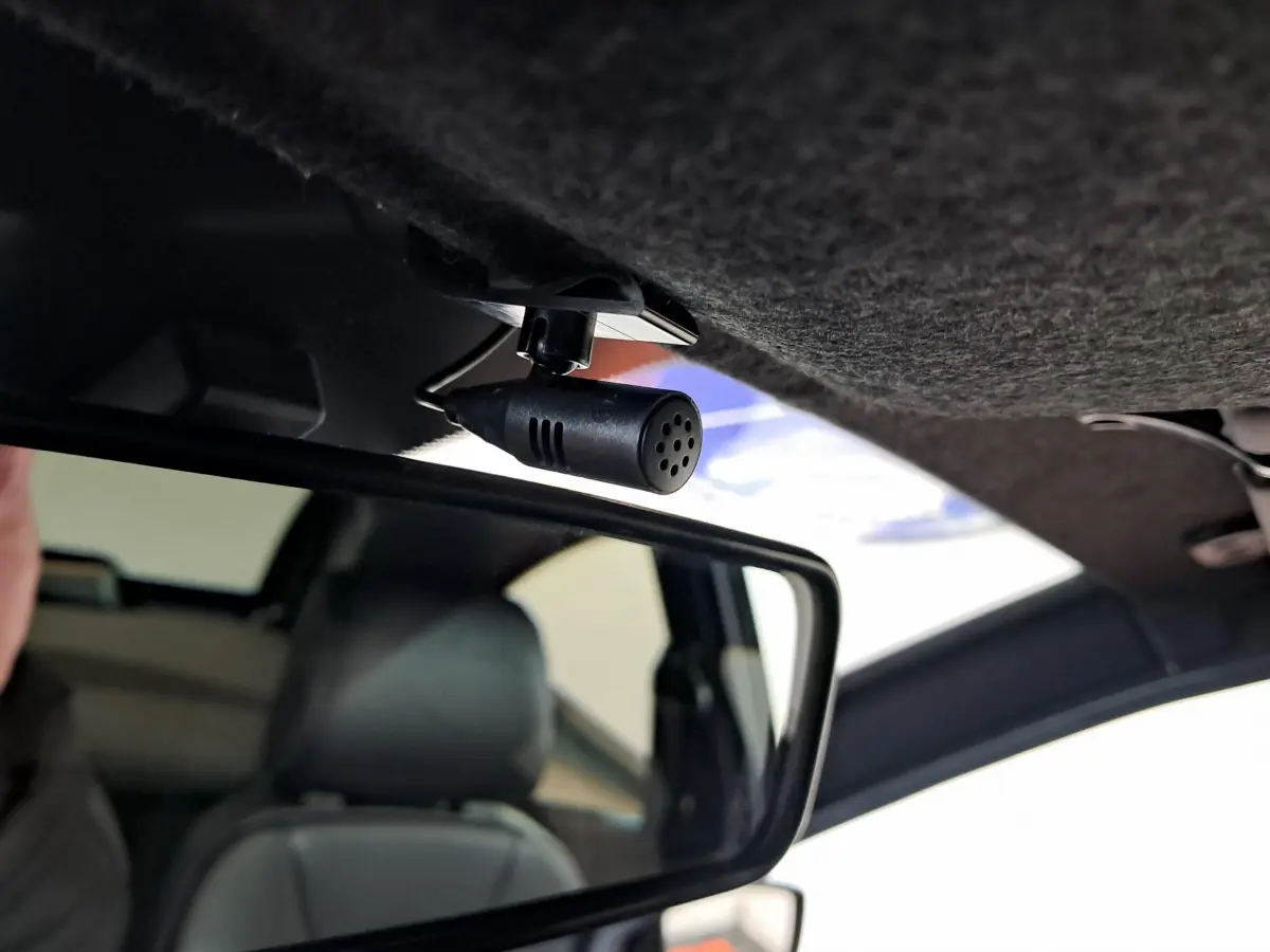 Microphone fixé au plafond intérieur au-dessus du rétroviseur dans une Aixam Ambition rouge 2025.